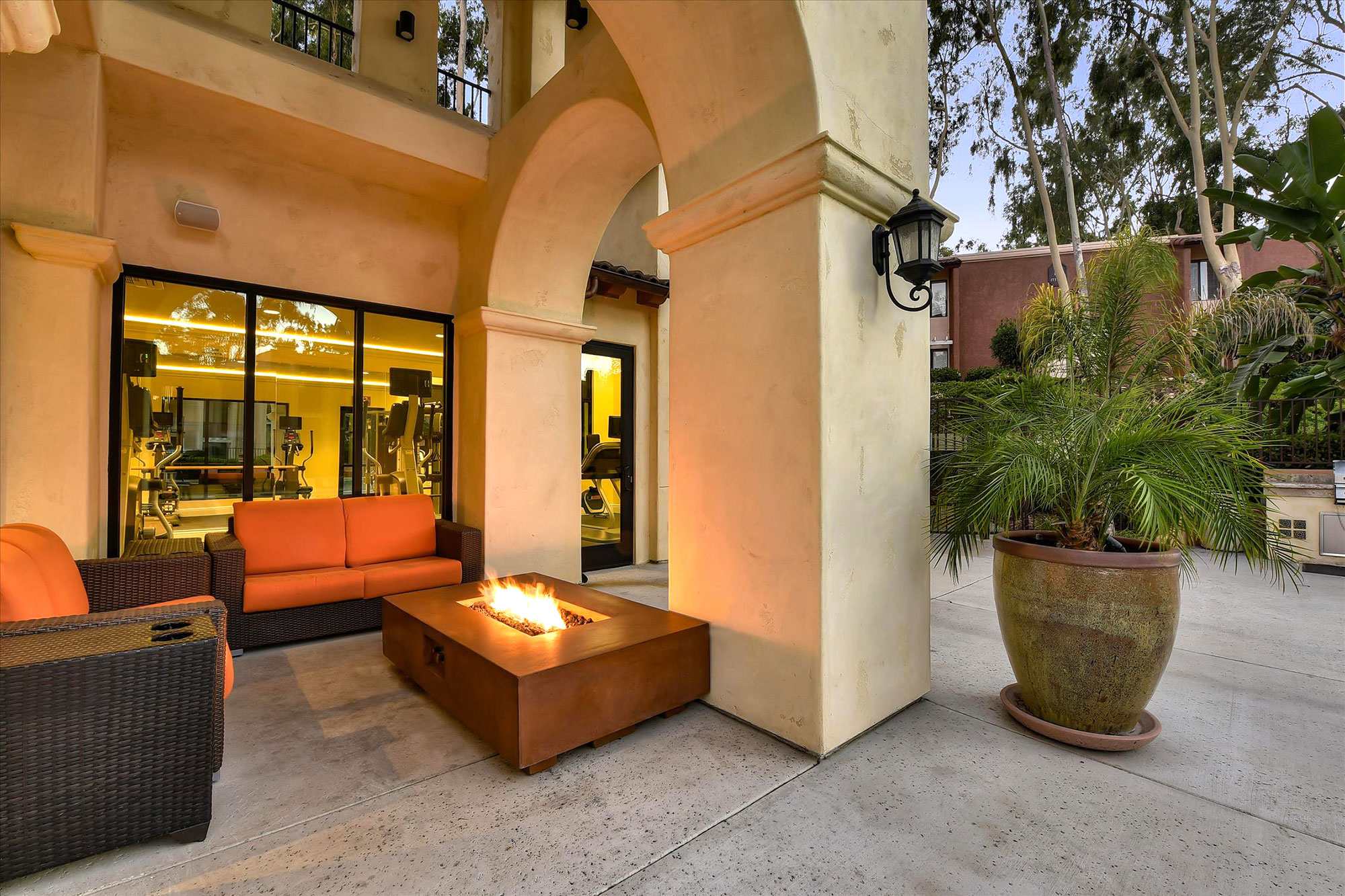 Exterior dusk shot of outside deck with tropical landscaping, covered seating, and a firepit