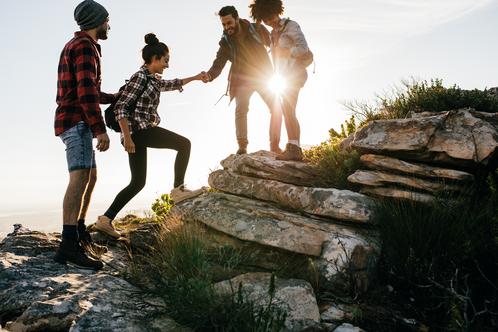 Young friends having fun outdoors, happy people enjoying harvest time together at farmhouse winery countryside, youth and friendship concept, hands toasting red wine glass at vineyard before sunset