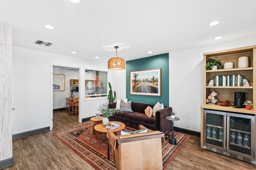 Leasing office with dark sofa, colorful pillows, and a framed desert landscape.