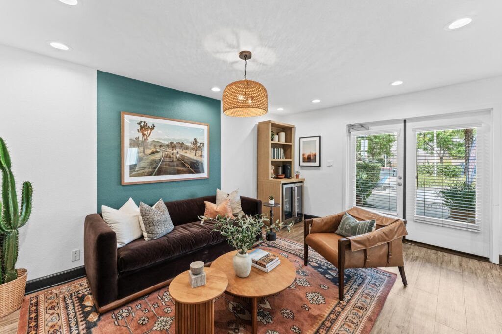 Leasing office with dark sofa, a teal accent wall with desert artwork.
