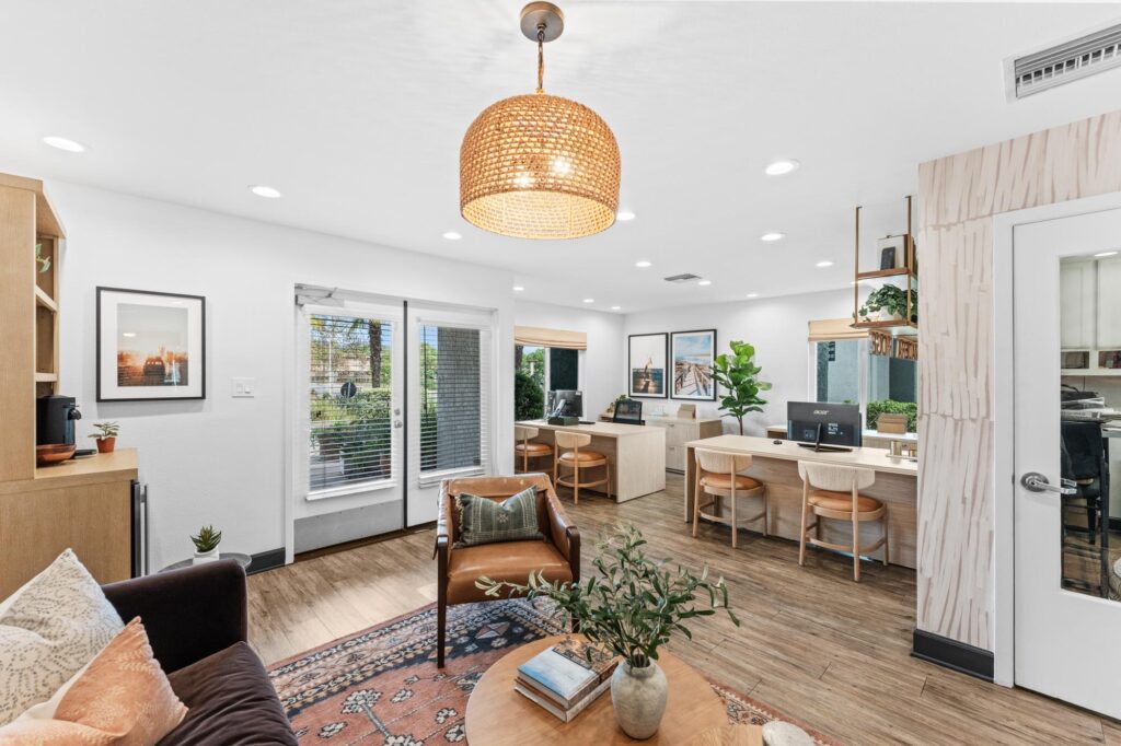 Leasing office lounge with wooden flooring, a central round table, chairs.