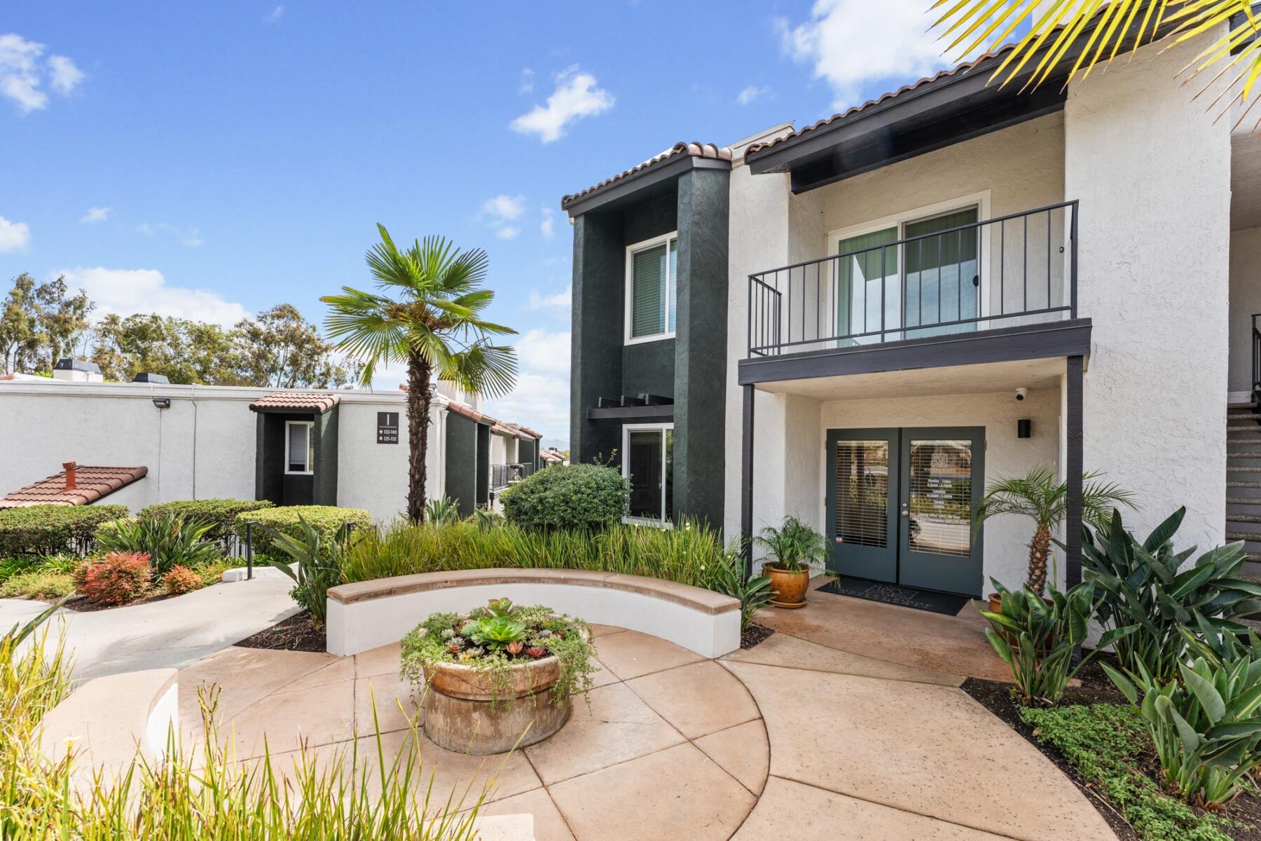 Leasing office on bottom floor of two floor apartment complex with balconies, and white and dark gray exterior.
