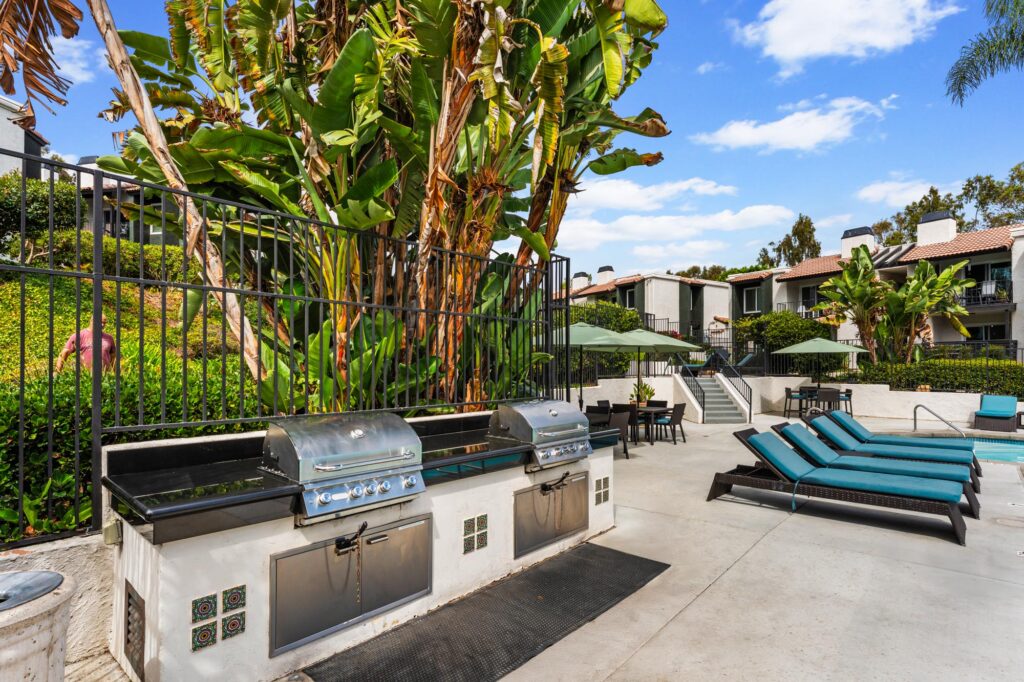 Grilling station with lounge chairs on pool deck.